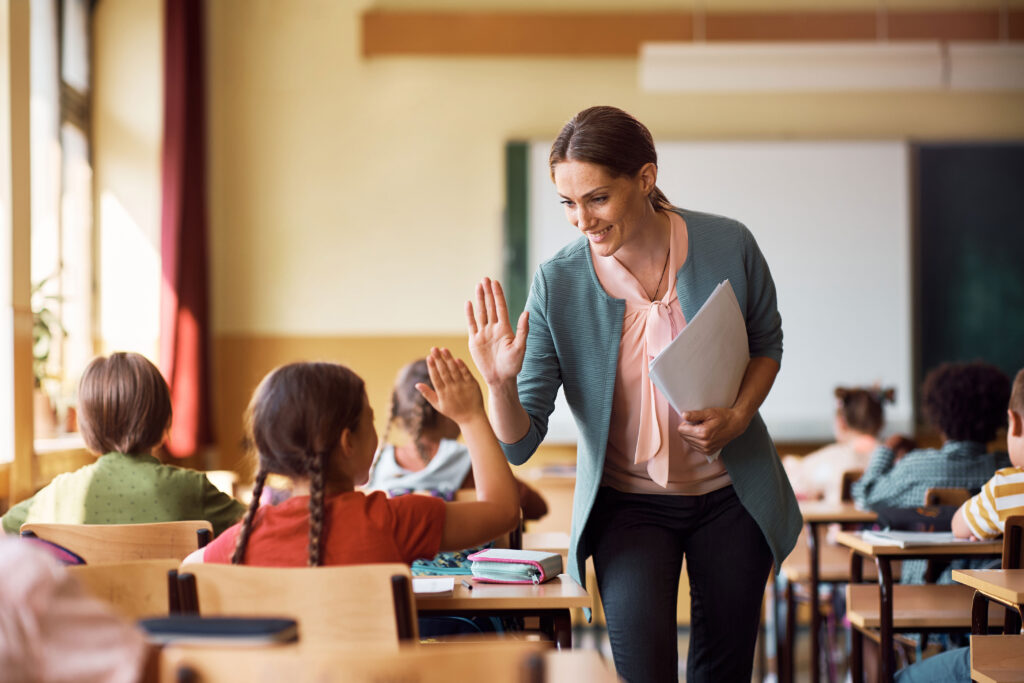 Eine Lehrerin klatscht sich mit Ihrer Schülerin ab